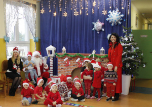 Grupa Kamyczki w świątecznej scenerii z św. Mikołajem, panią Dyrektor Agatą Ewą Ostalską i Zastępcą Wójta panią Iwoną Łuszcz-Krawczyk.