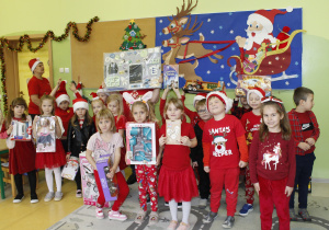 Przedszkolaki z grupy Zuchy trzymają w dłoniach świąteczne prezenty otrzymane od św. Mikołaja.