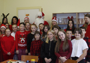 Mikołajki w klasie IV - zdjęcie grupowe uczniów z św. Mikołajem w towarzystwie pani Dyrektor i Zastępcy Wójta.