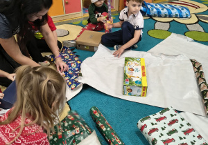 Słoneczka owijają papierem pudełka tekturowe.