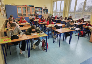 Uczniowie siedzą w ławkach i rozwiązują test wstępny.