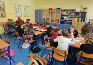 Uczniowie siedzą w trzech grupach.