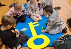 Uczniowie siedzą na materacu i ozdabiają klucz.