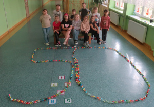 Uczniowie klasy drugiej prezentują na korytarzu szkolnym liczbę 50 wykonaną z papierowego łańcucha.