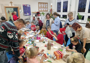 Rodzice udzielają dzieciom wskazówek, jak udekorować pierniki.