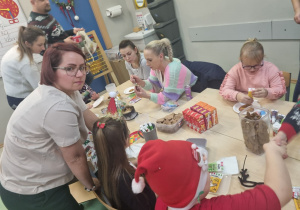 Rodzice pomagają dzieciom dekorować pierniki.