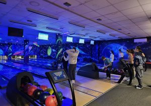 Grupa uczniów gra w kręgle.