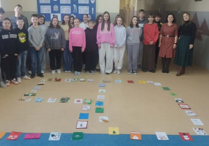 Uczniowie klasy 6 oraz Pani Marta Skoneczny i Pani Marta Płocka stoją za liczbą 50 ułożoną na podłodze z otrzymanych kartek świątecznych.