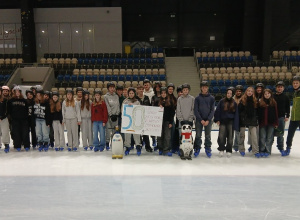 Uczniowie stoją na lodzie i trzymają plakat okolicznościowy z okazji 50 lecia.
