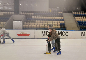Grupa uczniów jeżdżących na łyżwach na torze łyżwiarskim.