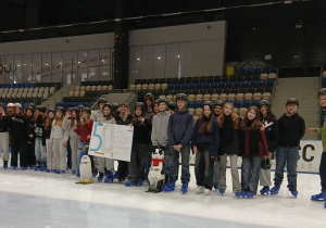 Grupa uczniów na lodowisku z plakatem jubileuszowym 50 lecia.