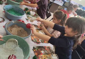 Dziewczynki posypują brokatem swoje bombki.