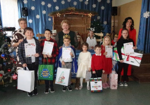 Laureaci konkursu na Najpiękniejszą Ozdobę Bożonarodzeniową z dyplomami i nagrodami ustawieni do zdjęcia z panią Kierownik, opiekunem Samorządu Uczniowskiego i panią Dyrektor.