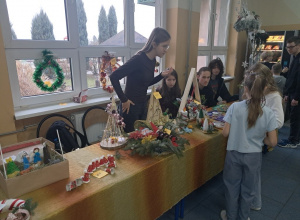 Uczniowie kl. VIII a sprzedają na korytarzu szkolnym ozdoby bożonarodzeniowe.