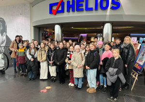 Uczniowie wraz z opiekunami przed wejściem do kina. W tle napis HELIOS.