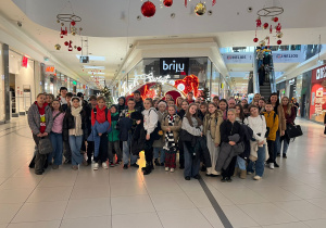 Uczniowie za zakończonym seansie z opiekunami na tle świątecznej dekoracji w Galerii.