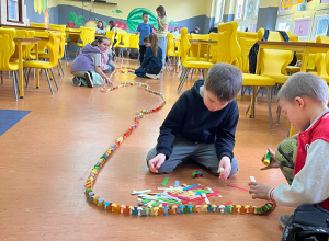 Uczniowie sklejają na podłodze papierowy łańcuch