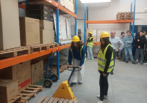 Uczennica obsługuje wózek paletowy.