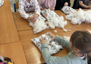Uczestnicy spotkanie wypełniają poduszki specjalnym puchem.