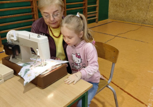 Praca dziecka przy maszynie do szycia z organizatorką spotkania .