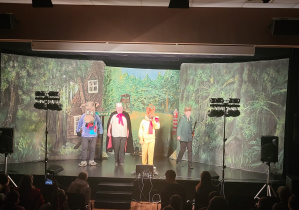 Aktorzy w pięknych kostiumach na scenie.