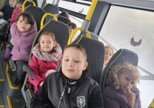 Uczniowie klas pierwszych siedzą wygodnie w fotelach w autobusie.