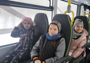 Chłopiec i dziewczynki siedzą wygodnie w autobusie.