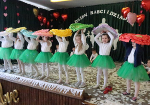 Dziewczynki trzymają kwiaty nad głowami.