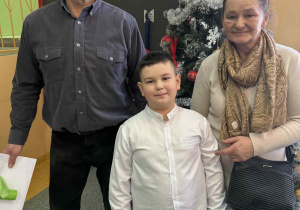 Dziadek z babcia z laurkami w kopercie z wnuczkiem.