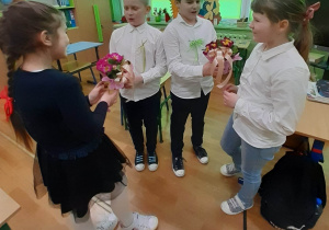 Kacpry z klasy III wręczają kwiaty koleżankom ze swojej klasy Oli i Marcie.