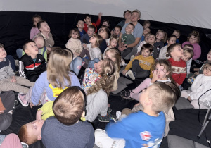 Przedszkolaki z zaciekawieniem oglądają seans filmowy z czasów prehistorii.