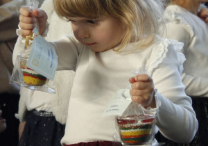 Dziewczynka z grupy Kamyczki trzyma w dłoniach własnoręcznie wykonany upominek dla babci i dziadka.