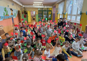 Przedszkolaki unoszą w górze czerwone karteczki - rozwiązują quiz dotyczący zasada bezpieczeństwa w ferii zimowych- "Zielone -czerwone" zabawa typu prawda -fałsz.