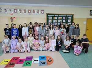 Uczniowie klas 4- 8 na szkolnym korytarzu w piżamach.