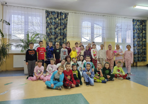 Uczniowie klas 1-3 wraz z nauczycielem na szkolnym korytarzu prezentują swoje piżamy.