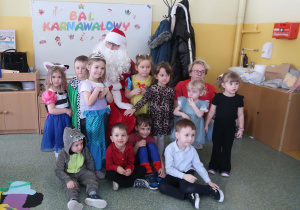 Grupa przedszkolna Słoneczka pozująca do zdjęcia ze Świętym Mikołajem.