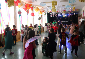 Grupa tańczących uczniów na balu karnawałowym.