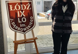 uczennica stoi obok tarczy liceum w Łodzi