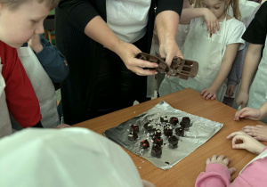 Dzieci oglądają jak wyjmować czekoladki z silikonowych foremek.