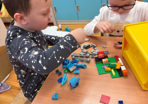Chłopcy z grupy 4-5 latków budują z klocków lego kosmiczny pojazd.