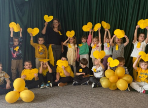 Dzieci z oddziału przedszkolnego z żółtymi sercami i balonami deklarują, że nie są obojętni na potrzeby innych.