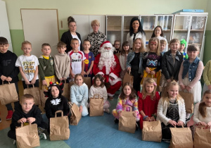 Uczniowie klasy I wraz z Panią Dyrektor, Mikołajem oraz przedstawicielami Rady Rodziców i wychowawcą prezentują swoje upominki.