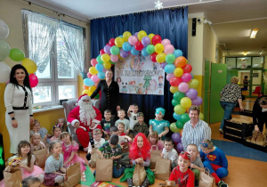 Grupa Zuchy wraz z Panią Dyrektor, Mikołajem oraz wychowawcą podczas zabawy choinkowej.