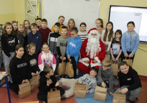 Uczniowie klasy IV wraz z Mikołajem prezentują swoje paczki.