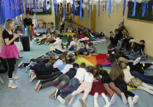 Uczniowie klas I -III leżą ma chuście klanza podczas zabawy choinkowej.