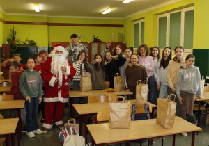 Uczniowie klasy V w raz z Mikołajem pozują do zdjęcia wraz z otrzymanymi prezentami.