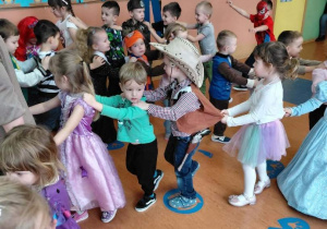 Przedszkolaki w pięknych strojach ustawieni w pociąg.