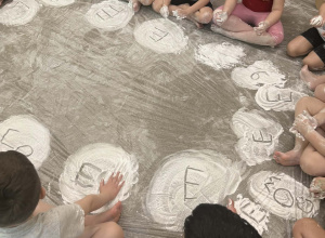 Dzieci z grupy Żabki siedzą na dywanie pokrytym śniegiem z białej pianki.