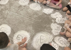 Dzieci z grupy Żabki siedzą na dywanie pokrytym śniegiem z białej pianki.