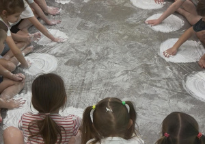 Dzieci z grupy Żabki rysują koła z białej pianki.